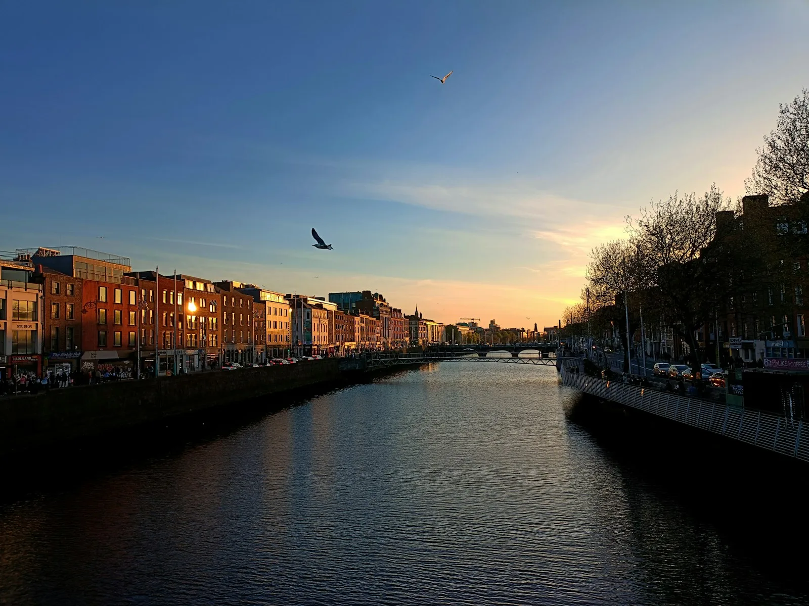 Panorámica del río Liffey y el puente Ha'penny iluminado al atardecer en Dublín