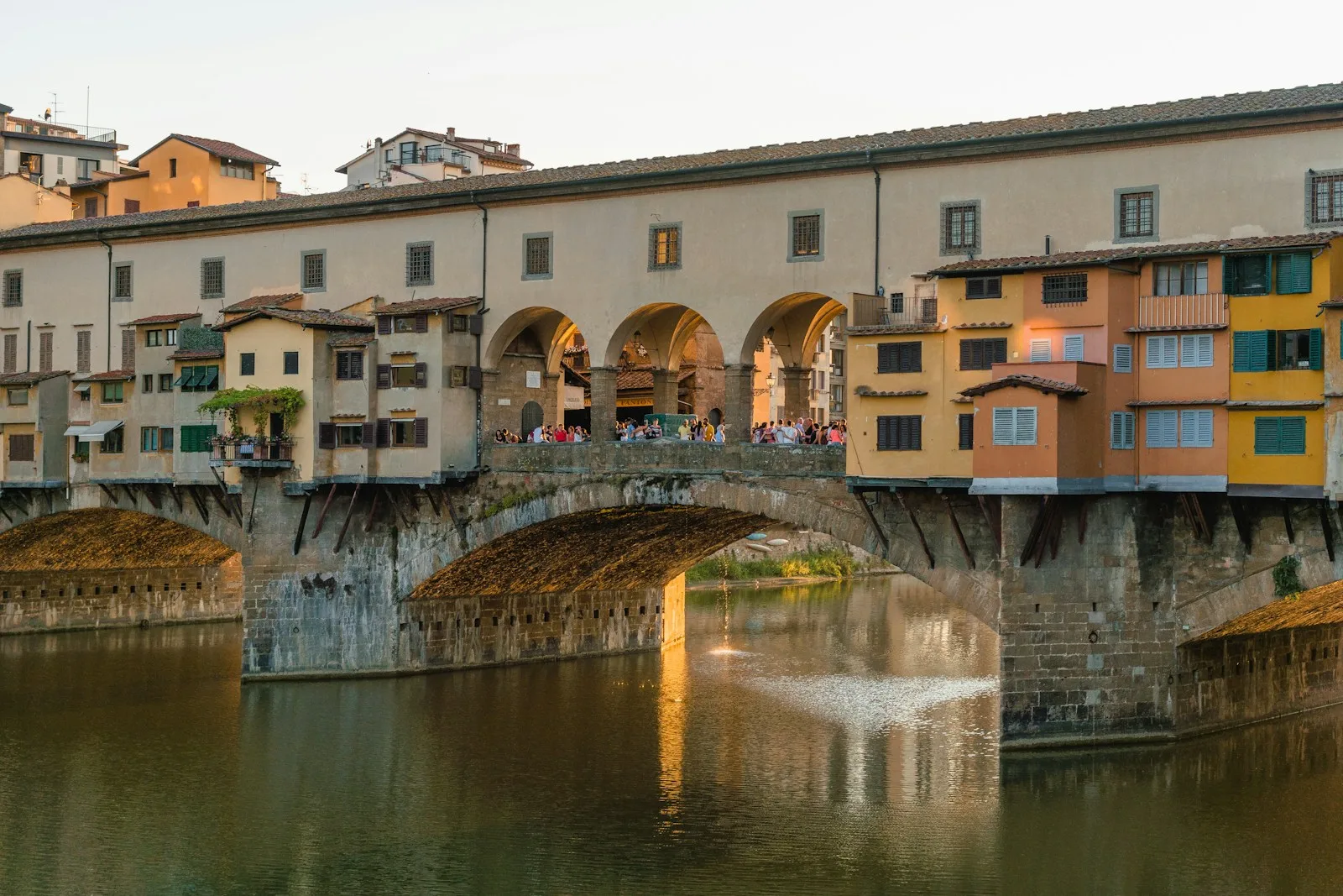 El histórico Ponte Vecchio medieval con sus tiendas colgantes reflejado en las aguas del río Arno