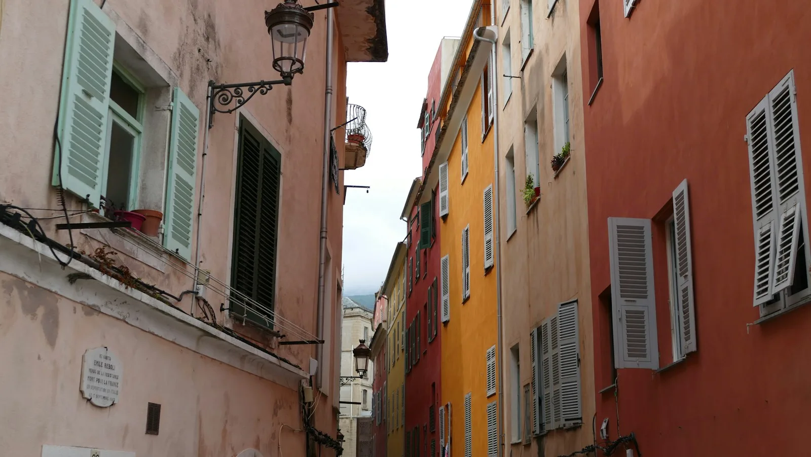 Callejuelas empedradas del casco antiguo de Niza flanqueadas por edificios ocres con contraventanas tradicionales