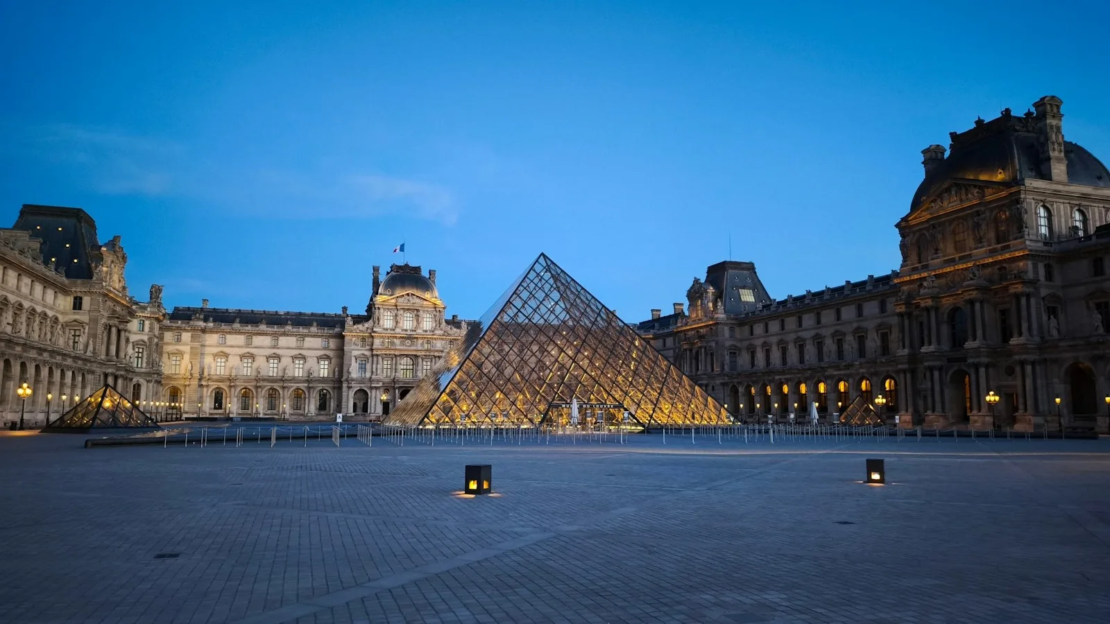 Pirámide de cristal del Museo del Louvre y palacio histórico al anochecer