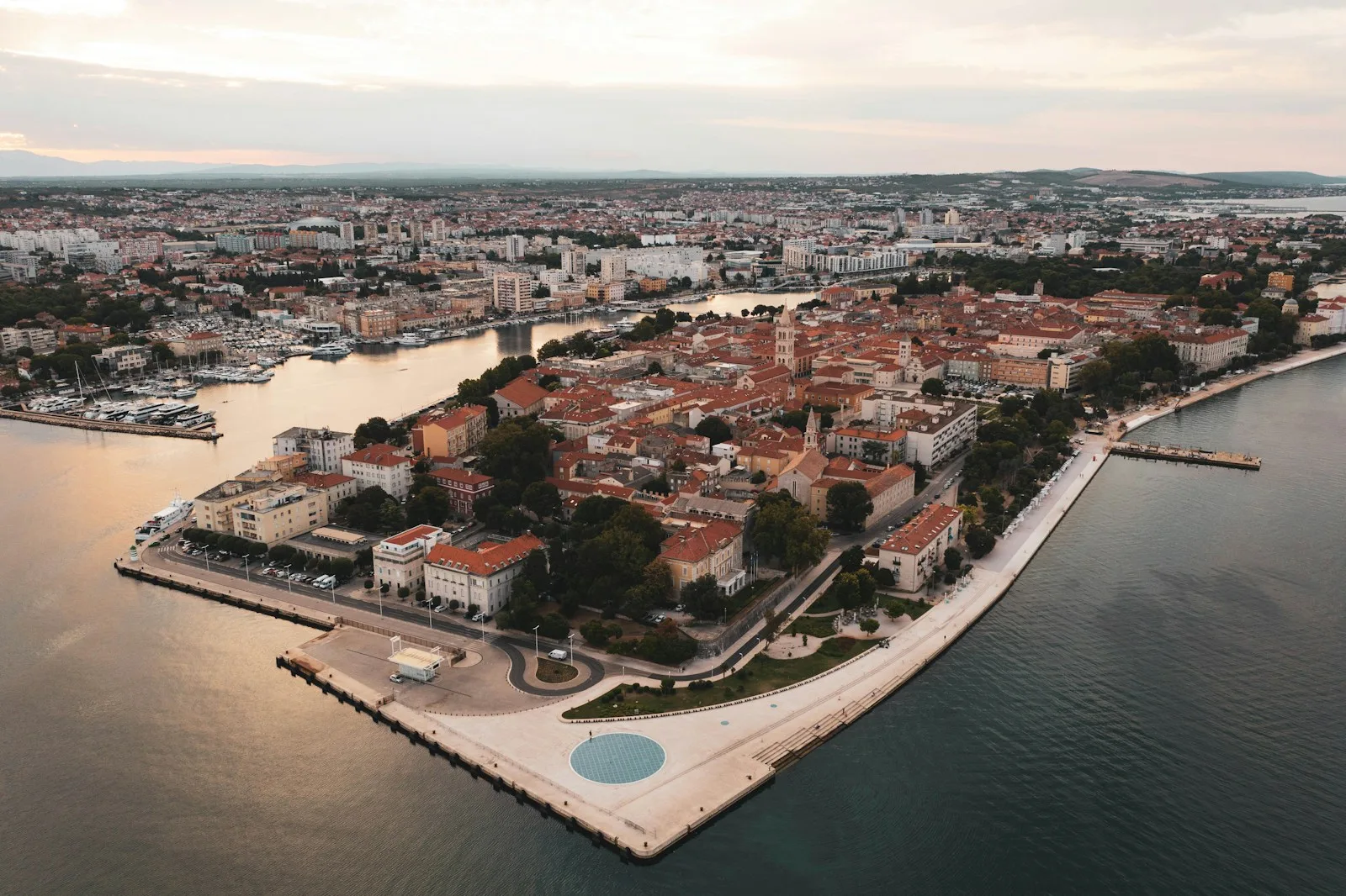 Fachada marítima de piedra blanca del Palacio de Diocleciano, paseo de la Riva y veleros en Split al atardecer