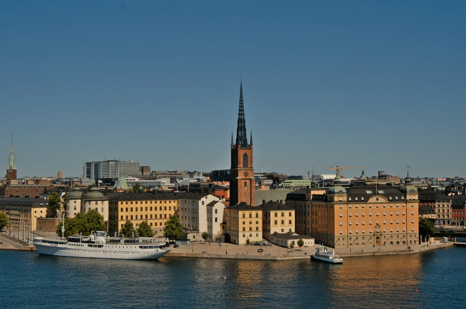 Torre de ladrillo rojo del Stadshuset de Estocolmo con las tres coronas doradas a orillas del lago Mälaren
